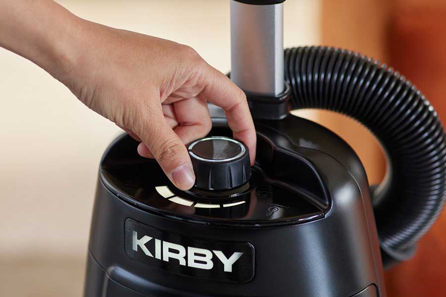 A close-up of a person's hand adjusting the Airflow Control dial on the top of a black Kirby Signature Series V530 upright vacuum cleaner, with the brand name clearly visible on the front.