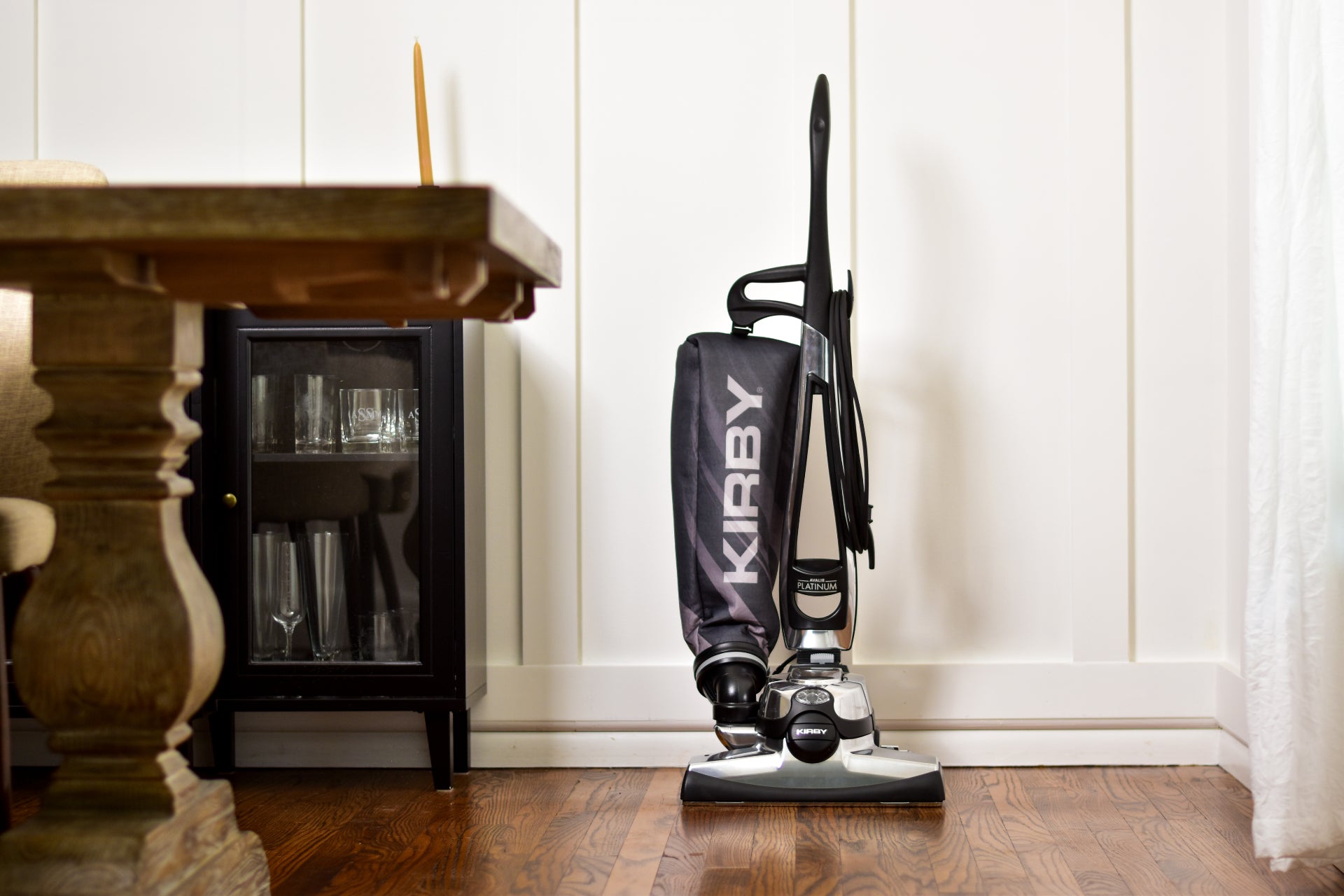 Kirby Avalir Platinum upright vacuum, black and silver, standing on a wooden floor.