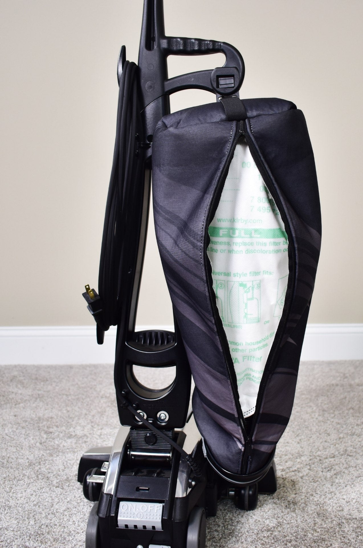 Person installing a white HEPA filter into a black Kirby vacuum cleaner.