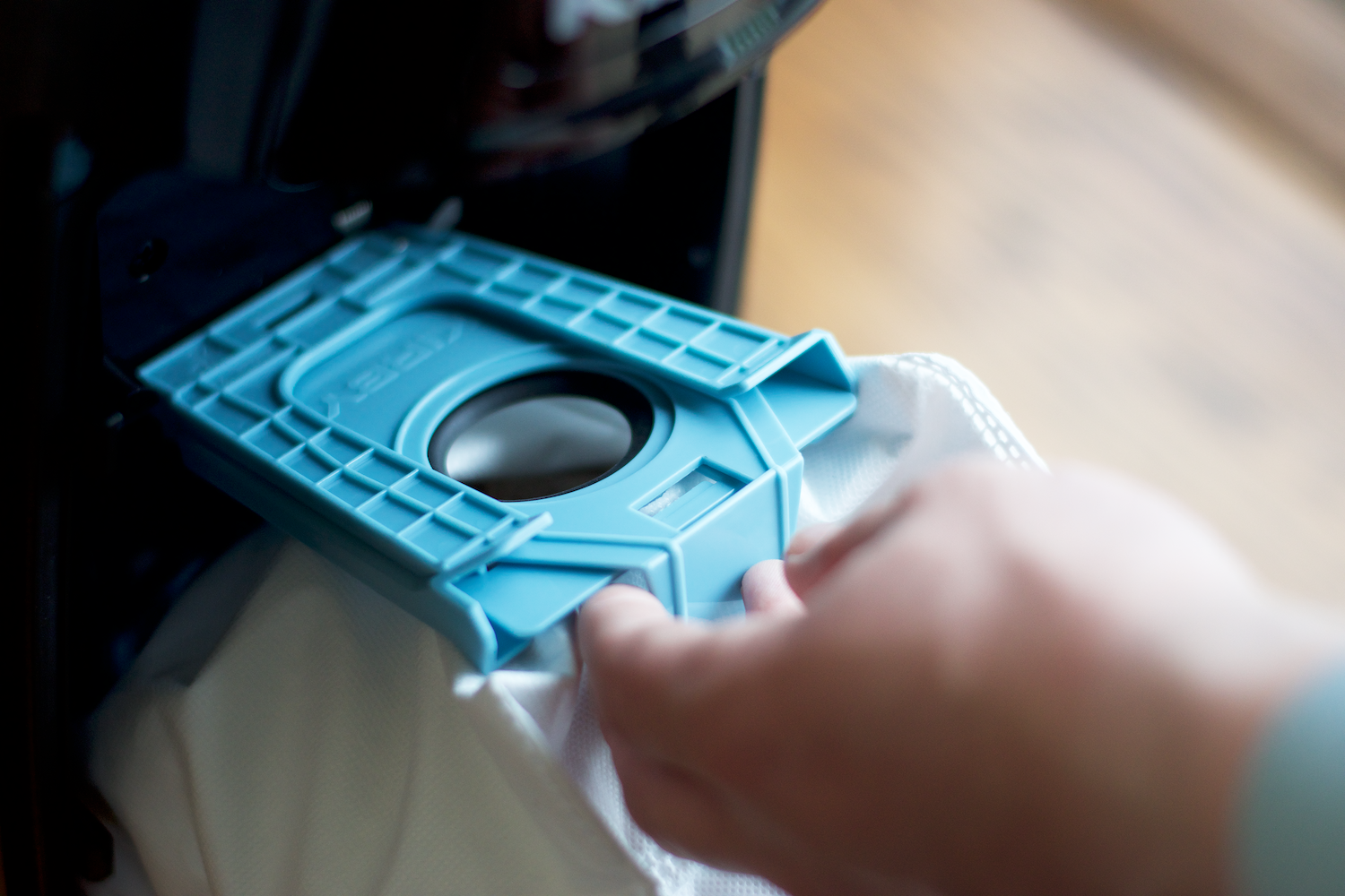 A person inserting a PureAir Dual-HEPA filter bag into a Kirby Signature Series V530 upright vacuum.