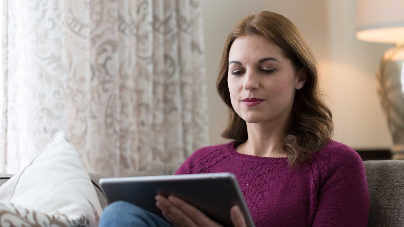 Woman using ipad to download the Kirby Vacuum Owner App.