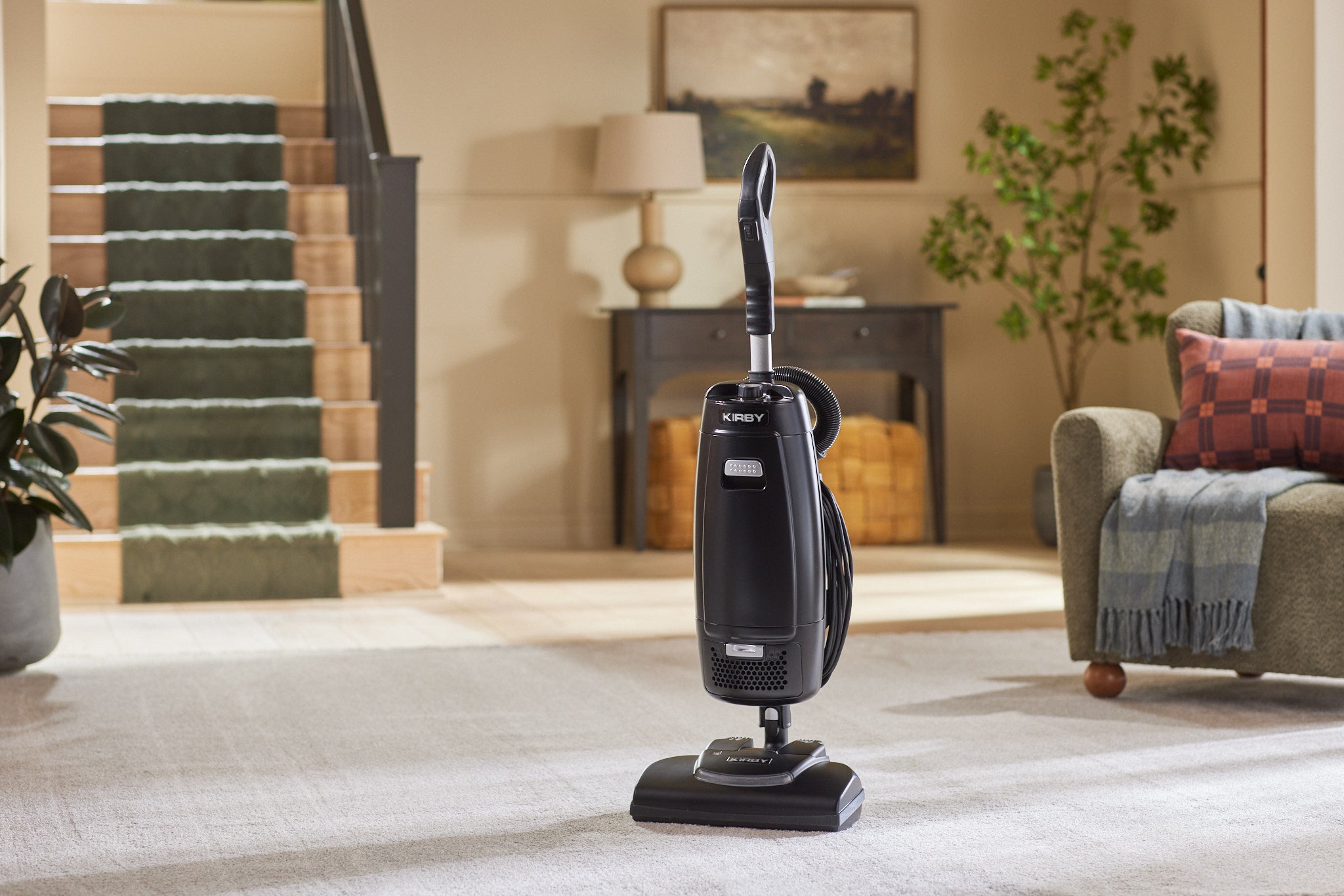 A black Kirby Signature Series V530 upright vacuum positioned on a light beige carpet in a living room.
