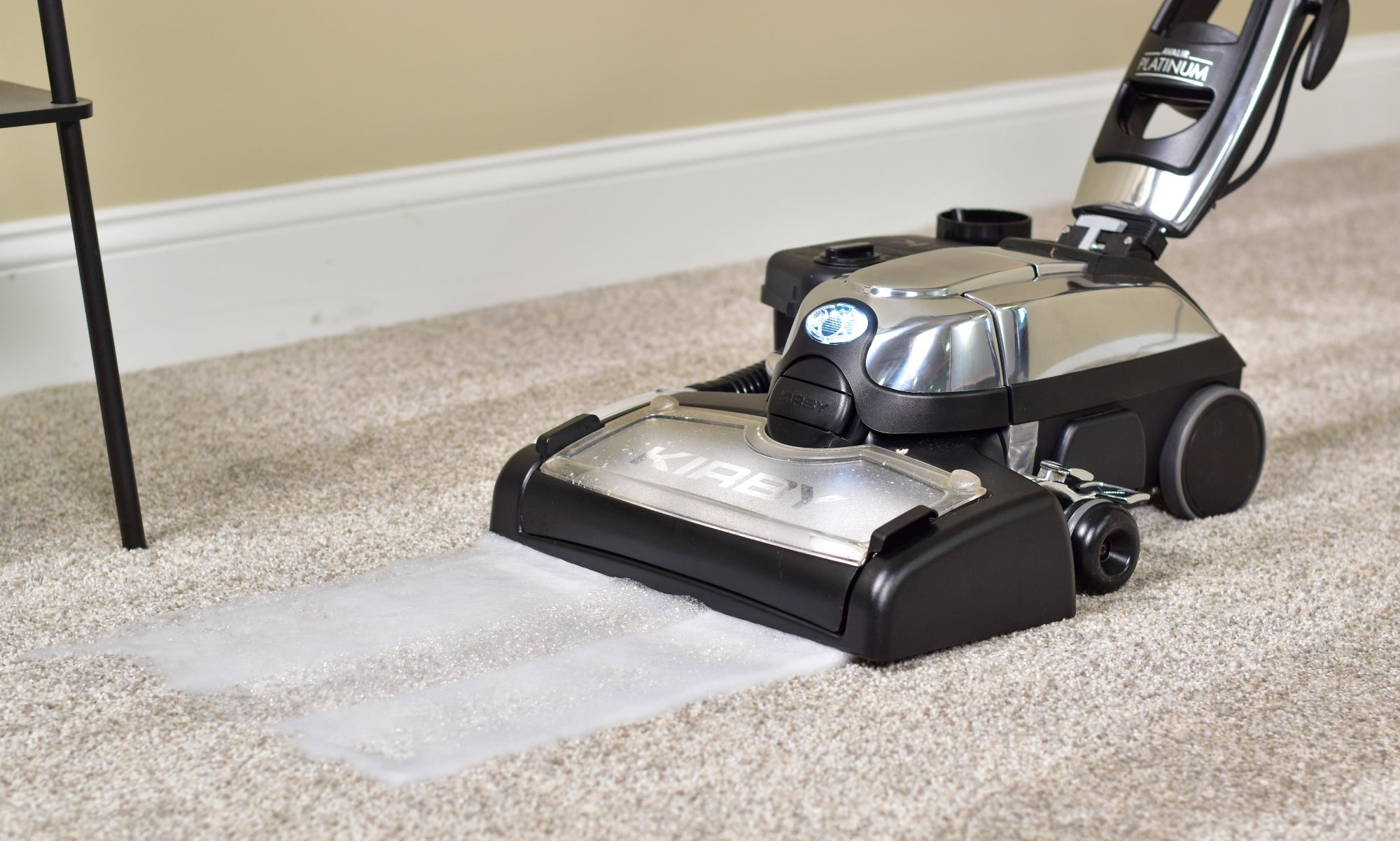 A Kirby vacuum with it's multi-surface shampoo system attached shampooing carpet
