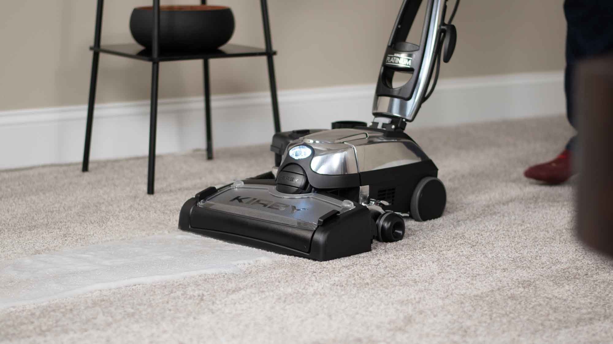 A Kirby vacuum with it's multi-surface shampoo system attached washing the carpet