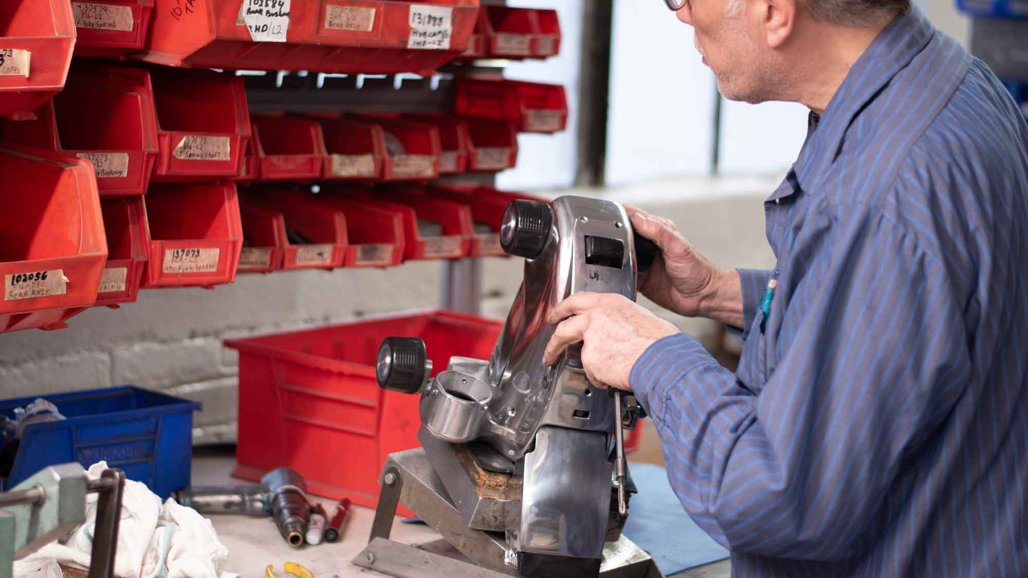 A man rebuilding an old Kirby vacuum in a factory