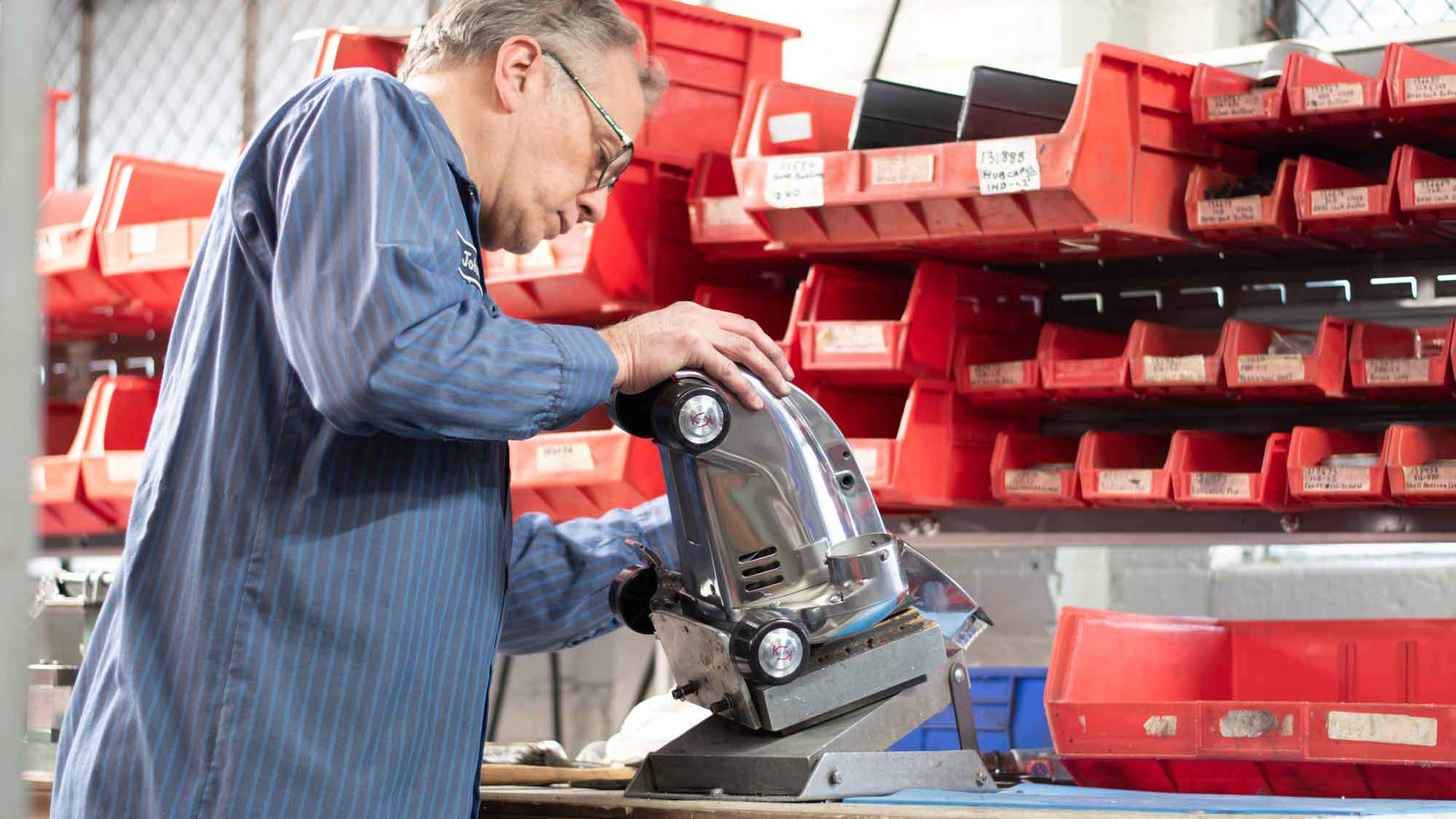 A man rebuilding an old Kirby vacuum in a factory
