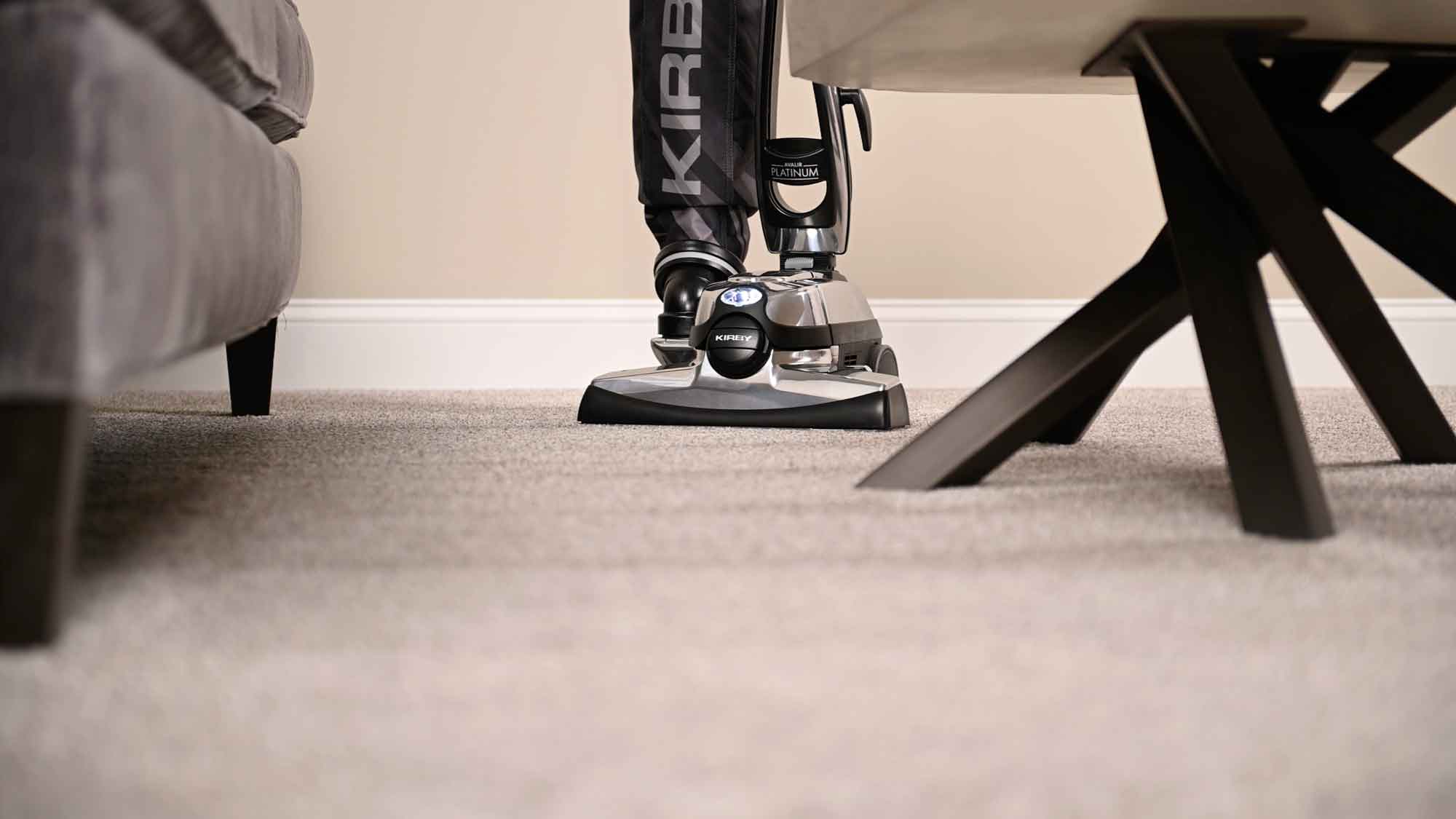 A Kirby vacuum that is sitting on the floor in the living room