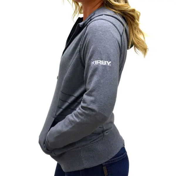 Woman wearing a light gray zip-up hoodie with "KIRBY" on the sleeve.