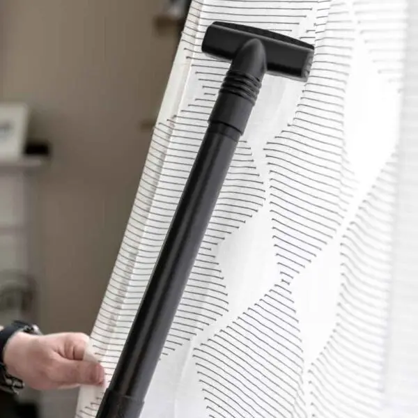 Black Kirby vacuum attachment cleaning white curtains.