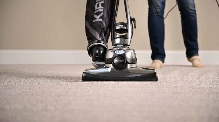 Kirby Avalir Platinum vacuum cleaner on carpet, person in jeans and socks in background.