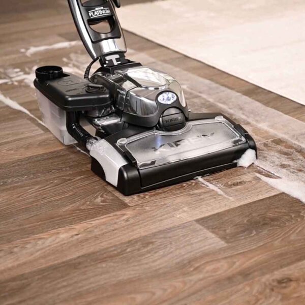 Kirby vacuum cleaner in silver and black, cleaning grime on a hardwood floor.