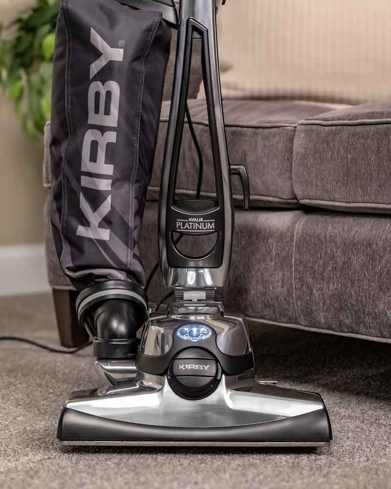 A Kirby vacuum in front of a couch