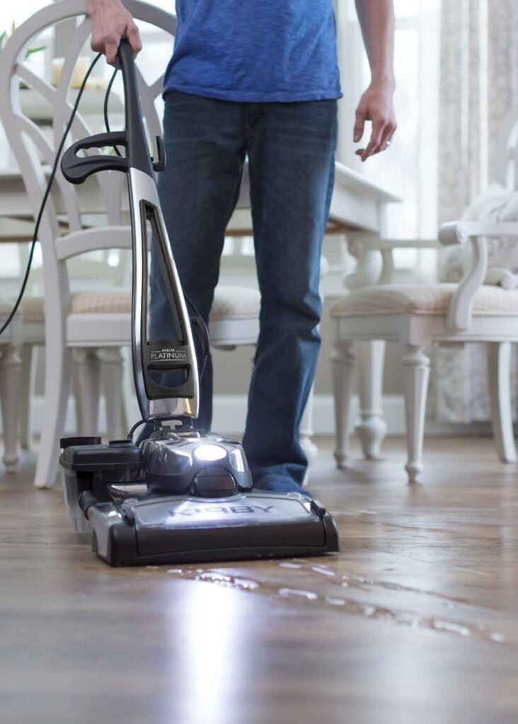 Person using a Kirby Avalir Platinum vacuum cleaner on a wooden floor.