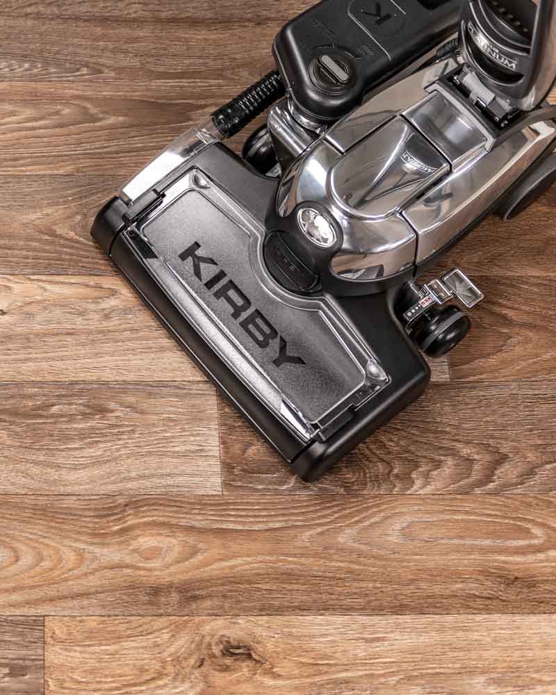 Kirby Avalir Platinum Upright vacuum on hardwood floor, silver and black.