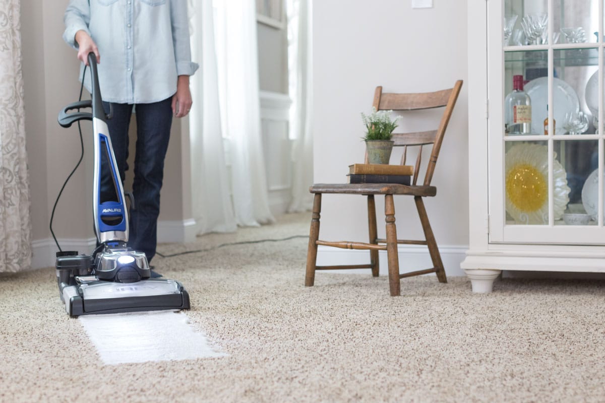 A man using a Kirby vacuum with it's multi-surface shampoo system to clean the carpet