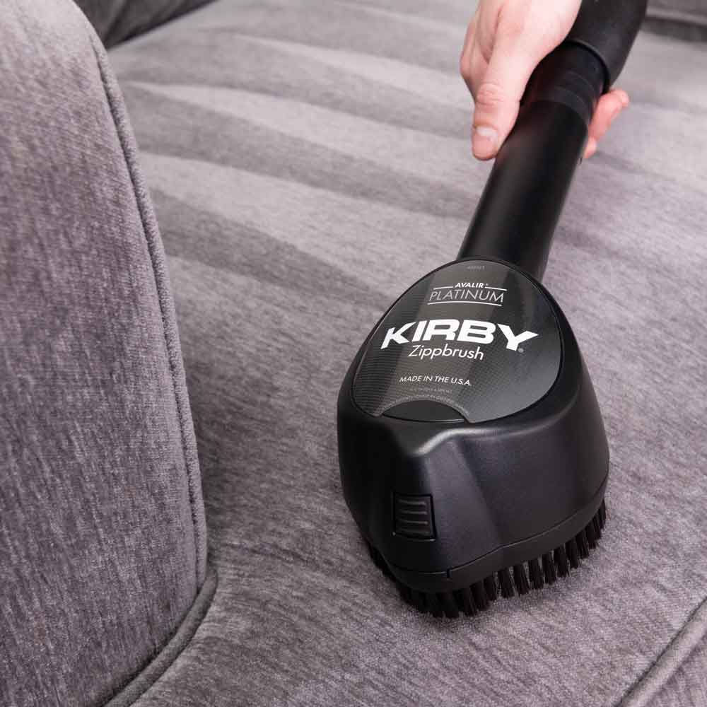 Kirby Zippbrush vacuum attachment cleaning a gray couch.