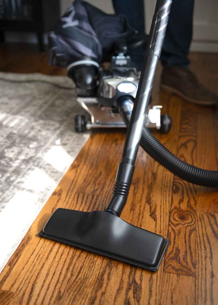 Kirby vacuum in canister mode cleaning a hardwood floor.