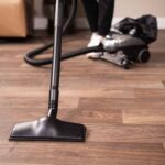 Kirby vacuum in canister mode, black and silver, on wooden floor.