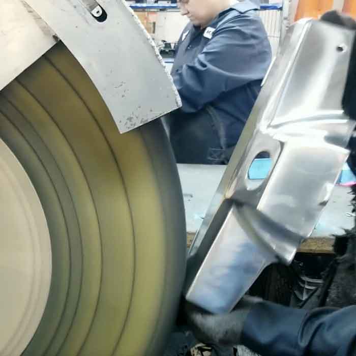 Worker polishing a large, metallic Kirby vacuum part.