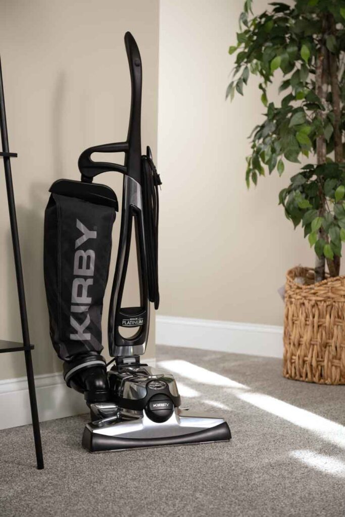 Kirby vacuum cleaner, black and silver, standing upright on a carpet.